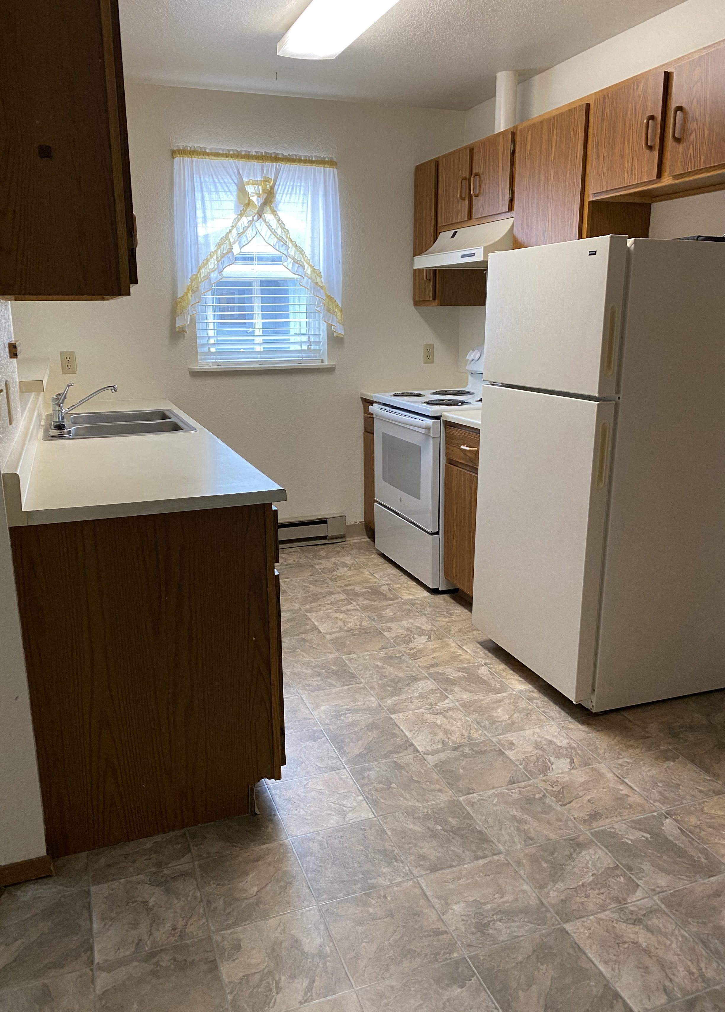 Image of refrigerator, stove, sink, cabinets, and window